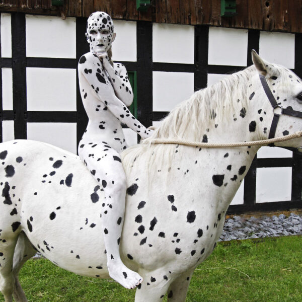 Künstler Jörg Düsterwald hat für das Kunstprojekt ANIMAL ART ein Fotomodell vollständig weiß mit schwarzen Flecken bemalt. Die Frau sitzt auf einem Pferd, welches genauso aussieht.