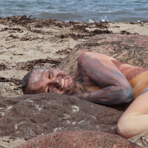 Ein nacktes Fotomodell wird für das Kunstprojekt Natureart von Künstler Jörg Düsterwald vollständig so mit Farbe bemalt, dass die Person mit der Kulisse verschmilzt.