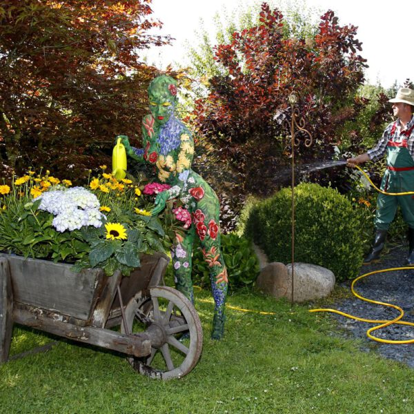 Für das Kunstprojekt WORKING ART, bei dem Berufe mit Bodypaintingmodellen dargestellt werden, hat Künstler Jörg Düsterwald ein Fotomodell vollständig bemalt. Die mit Blumenmuster gestylte Frau hält sich zusammen mit einem Gärtner in einem Garten auf.