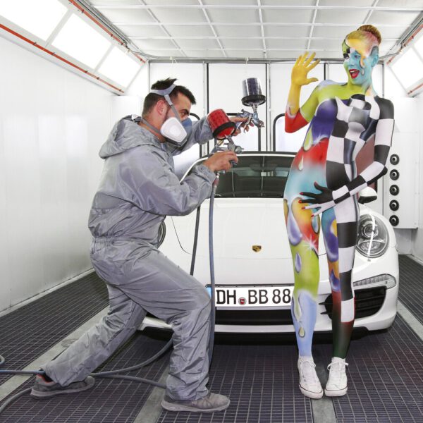 Für das Kunstprojekt WORKING ART, bei dem Berufe mit Bodypaintingmodellen dargestellt werden, hat Künstler Jörg Düsterwald ein Fotomodell vollständig bemalt. Die bunt gestylte Frau hält sich zusammen mit einem Lackierer und einem Sportwagen in einer Lackierkabine auf.