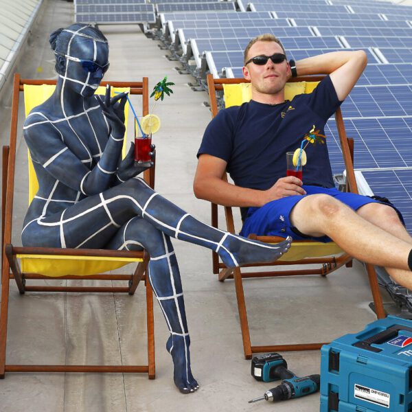 Für das Kunstprojekt WORKING ART, bei dem Berufe mit Bodypaintingmodellen dargestellt werden, hat Künstler Jörg Düsterwald ein Fotomodell vollständig bemalt. Die gestylte Frau trägt ein Solarpanel-Muster und hält sich zusammen mit einem Monteur bei einer Photovoltaikanlage auf.
