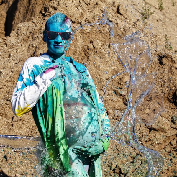 Für das Outdoor-Projekt SPLASH ART hat Künstler Jörg Düsterwald ein schwangeres Fotomodell mit Körperfarbe bemalt und anschließend in einem Sandabaugelände mit flüssiger Farbe und Wasser übergossen.