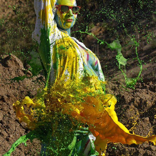 Für das Outdoor-Projekt SPLASH ART hat Künstler Jörg Düsterwald ein schwangeres Fotomodell mit Körperfarbe bemalt und anschließend in einem Sandabaugelände mit flüssiger Farbe übergossen.